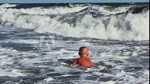 A child swims in the Sea of Azov. A boy jumps into the sea waves from the beach. The boy dives into the foaming wave. The delight of a child from a vacation at the sea. Happy moments with children. 4K