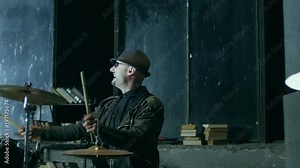 Professional stylish rock drummer playing on drum set with crazy emotions and jumping and falling down in slow motion 200 fps . Shot on RED HELIUM Cinema Camera.