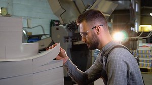 Print worker ready to place blank sheets of paper into offset machine for printing.