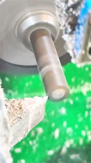 Rotating lathe shapes metal cylinder with flying shavings
