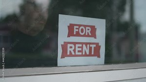 Placing a FOR RENT Sign in The Window of a Building