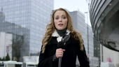 Wide locked down shot of a Caucasian female news reporter reporting...