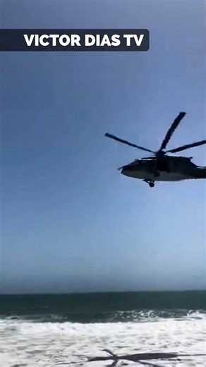 A shocking phone video from the Venezuelan coast shows civilians frozen in disbelief as military aircraft suddenly emerge from over the ocean. The shaky vertical footage captures the calm shoreline breaking into chaos when the thunder of helicopter rotors erupts and Black Hawk helicopters rise low on the horizon. As ocean spray is violently disturbed below, fighter jets blast overhead moments later, shaking the camera and triggering panicked reactions from the crowd. The aircraft quickly move in
