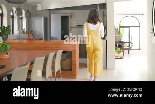 Mature woman in overalls entering kitchen moving to island checking phone opening laptop preparing. Adult, workwear, device, computer, home, modern, bright Stock Video Footage - Alamy