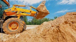 A tractor digs a hole at a construction site. Working process at a construction site. Tractor bucket close up