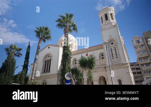 Wide angle view of Ayia Napa Cathedral in Limassol, Cyprus, featuring a traditional Orthodox church with a central dome and bell tower surrounded by palm trees under a clear blue sky Stock Video Footage - Alamy