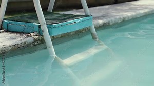 Private swimming pool with white painted metal stairs and handrail, pool ladder under the water of the pool, staircases for descending into the pool water during relax time