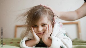 little girl dries her hair with a hair dryer at home.