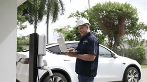 Qualified technician working on home EV charging station installation, making troubleshooting and configuration setup on charging system with laptop for EV at home. Fastidious
