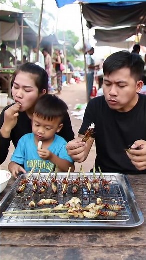 Asian Family Eating Grilled Larvae Skewers at an Food Market.