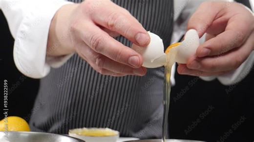 Chef cracking egg in bowl cooking food. Slow motion. Fresh white egg being cracked in yolk falls out of frame. 4 k video