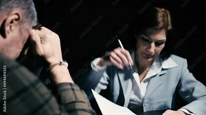 Female police detective questioning man in handcuffs, suspect crying, confession