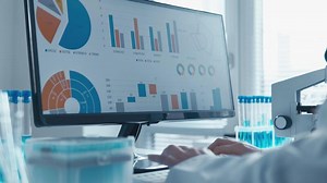 In a bright lab with test tubes and scientific equipment, a dedicated researcher analyzes data on a computer screen, showcasing colorful charts and graphs of their findings in biotechnology