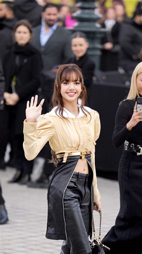 Brand Ambassador di Louis Vuitton, in occasione del fashion show della maison nell’ultimo giorno della Settimana della Moda parigina, Lisa non poteva non prendere parte al front row della sfilata per la presentazione della collezione FW26. Lisa indossa un top in duplice materia, composto da una camicia color crema con maniche a sbuffo e ruches, segnata sotto il petto da un sottile dettaglio dorato; da lì il capo si apre in pelle nera lungo le lunghezze. A completare il look, un pantalone bootcut