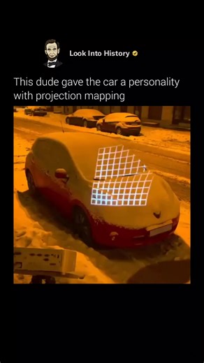 Look Into History on Instagram: "Russian creator Nikita Merkushin, known as noizebro, shows how far projection mapping can go by turning a snow-covered Nissan Leaf into a living character on a quiet city street at night 🚗❄️ Using a home projector and software like Cinema 4D, he precisely maps animated visuals onto the car’s curves, giving it blinking cartoon eyes, a smiling mouth, and playful expressions. The car winks, looks around, and reacts as if it’s aware of its surroundings, instantly fe