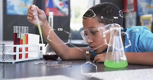 Conducting science experiment, child with safety goggles using pipette over chemical formulas