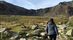 A plus-sized woman hikes along a trail at Llyn Idwal on a beautiful Autumn day - Snowdonia National Park, Wales, UK