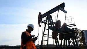 Man (Engineer, Manager, Supervisor, oilman) with tablet computer inspects the oil pumping unit.