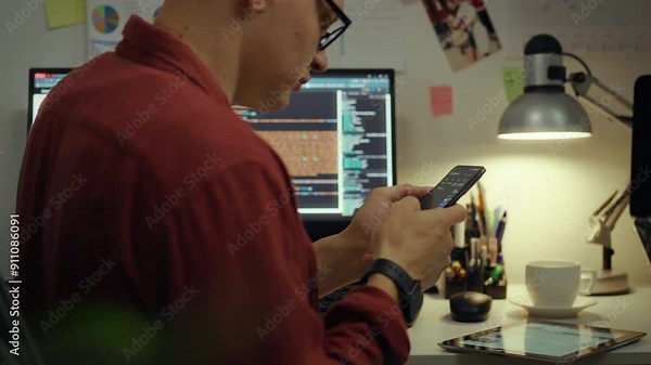 Programming. European guy is attentively immersed in virtual space in the evening room. Cinematic shot of a remote access worker working with a modern smartphone applies new coding methods, data