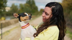 Young woman and her dog kissing each other in slow-motion outdoors.