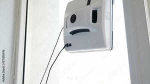 Clean service. Modern way of windows cleaning. Robotic glass washer moving and rotating on window in private apartment. Automatic glass washer working on the window of apartment, close-up. 4k