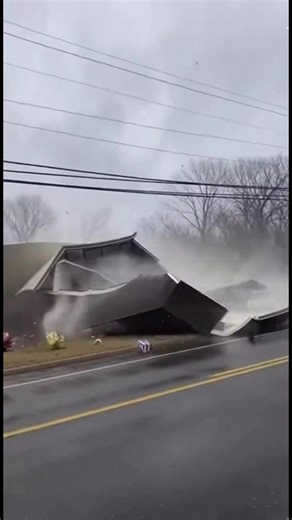 Cell phone footage captured during a severe windstorm appears to show an entire Dollar General store lifting off its foundation before flipping into the parking lot. Witnesses recorded the building shaking violently as powerful gusts intensified. Within seconds, the full structure rose into the air and overturned, slamming into parked vehicles and breaking apart under the force of the storm. Debris scattered across the roadway as power lines snapped and sparks flashed in the aftermath. | Branson