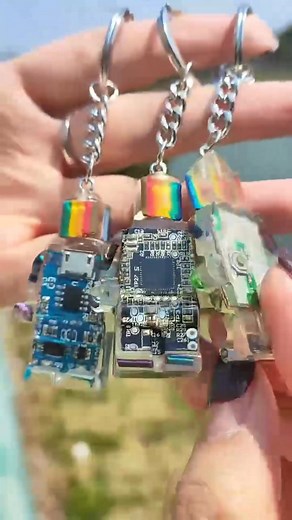 These unique robot keychains and pendant feature authentic upcycled circuit boards preserved in crystal-clear resin, creating a perfect blend of tech and art. Each piece showcases real electronic components with rainbow accents, making them ideal gifts for tech enthusiasts, IT professionals, or anyone who appreciates innovative accessories. | Readilyine