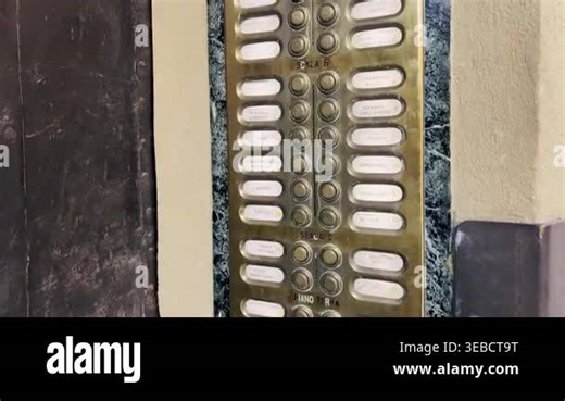 Detailed view of a retro bronze intercom panel with multiple doorbells and nameplates, set in a green marble wall, capturing the nostalgic aesthetic of a historic European apartment building Stock Video Footage - Alamy
