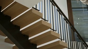Modern staircase with wooden steps and black metal railing. Steps floating, giving staircase sleek and contemporary look. Design is minimalist and stylish