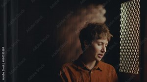 Young regretful woman speaking through perforated screen of confession booth when having private conversation with priest in church