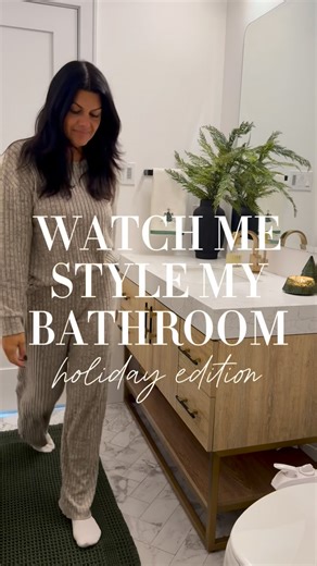 Emilia Aquino | Always Stylish Home on Instagram: "Follow + type HOLIDAY BATH for a 🔗 I couldn’t resist the viral bath mat in this stunning green—instantly sets the holiday vibe and yes… it’s 100% worth the hype. I swapped in a taller vase with pine stems for height, added the cutest Christmas-tree towels, a little gold reindeer moment, and the prettiest green mercury-glass tree candle (it smells incredible). Then I finished it off with a DIY swag of pine and brown ribbon draped over my wall ar