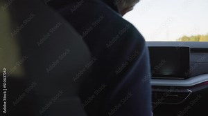 A man gets into his luxurious car and gets ready to drive - rear closeup from the backseat