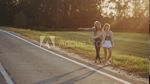 Two traveller women hitchhiking on remote rural road Loa, Utah, United States. Cars pass by. Lonely girls want to catch a car. Road trip travel around the world. Adventure journey. Tourists get lost