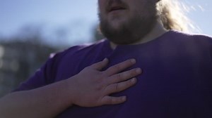 One overweight man with hand in chest having difficulty to breath. A fat person having heart pain