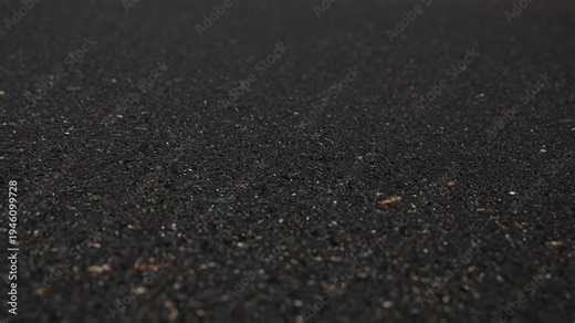 Slow motion video of the fresh asphalt surface in Siska, Ljubljana, a base of compacted grey aggregate and a thick, fresh layer of black asphalt.