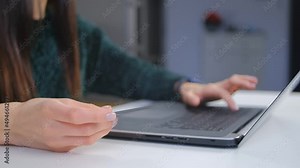 Woman paying with credit card online. Young female making a purchase in internet store with bank debit card and laptop computer