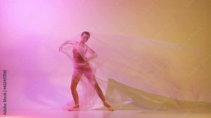 Flexible, tender yung girl, professional ballerina dancing with transparent veil against gradient pink yellow studio background in neon light. Concept of classical art, dance, beauty, inspiration