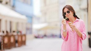 Young female model eating ice cream cone outdoors. Summer concept - woamn with sweet ice-cream at hot day