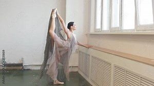 Beautful ballet dancer in flying fabric dress, like the fabulous nymph lifting her leg up and stratching her arm forward during final reheasal before concert