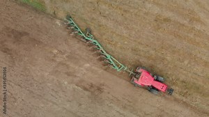 Aerial view of a modern tractor with a multi-plow on farmland, cultivating the soil for sowing. Agricultural machine is controlled by a GPS precise positioning system