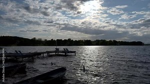 Sunset over the lake. View of the pier with deck chairs by the water.