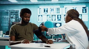General practitioner measuring blood pressure with a blood pressure monitor, checking the pulse and heartbeat with a modern tool. Cardio control measurement and readings in a cabinet. Camera B.