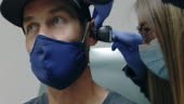 A Female Physician Assistant Wearing a Surgical Face Mask Uses an...