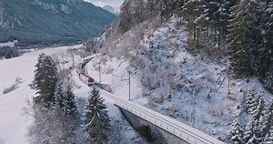 Landwasser Viaduct world heritage sight with luxury Glacier and Bernina express in Swiss Alps snow winter scenery. Aerial Drone shot red train passing through famous mountain in Filisur, Switzerland.