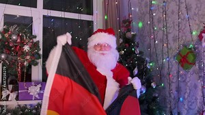 Santa Claus with German flag in hands emotional dances to Xmas party, among festive decorations with Christmas tree and glowing garlands. New Year in Germany.