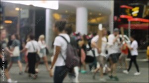 Crowded intersection with pedestrians crossing by in a busy environment. There is a police car in the background.