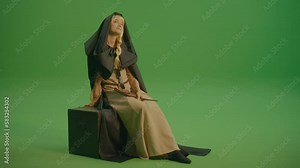 Green Screen. Woman Sorceress With a Magic Wand Sitting on the Magic Chest and Casts a Spell. Fairy-tale Image: a Girl in a Medieval Dress Makes Wishes, Like a Princess From a Fairy Tale.