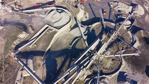 Overhead view captures the dynamic activity of heavy machinery and conveyors at a mining site, where raw materials are processed and moved expertly during daylight.