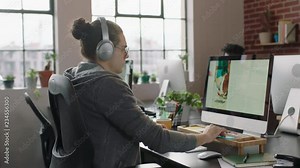 young caucasian businessman designer working on graphic design project using computer listening to music enjoying writing notes brainstorming ideas in relaxed office workplace