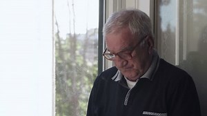 Bored old man looks at the window smoking a cigarette